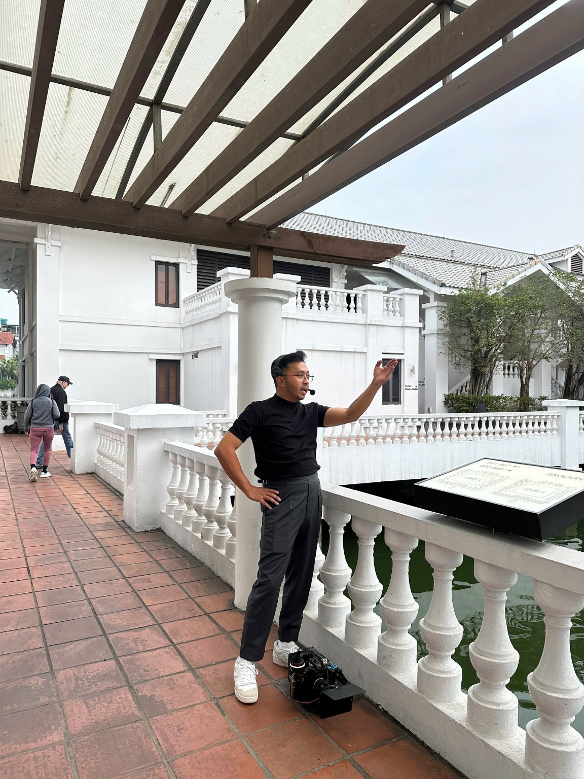 Khoa Huỳnh đeo tai nghe, trao đổi tại điểm quay ngoài trời